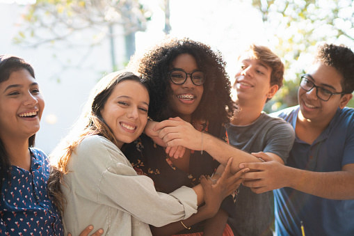 a group of affectionate teenage friends walking in a park