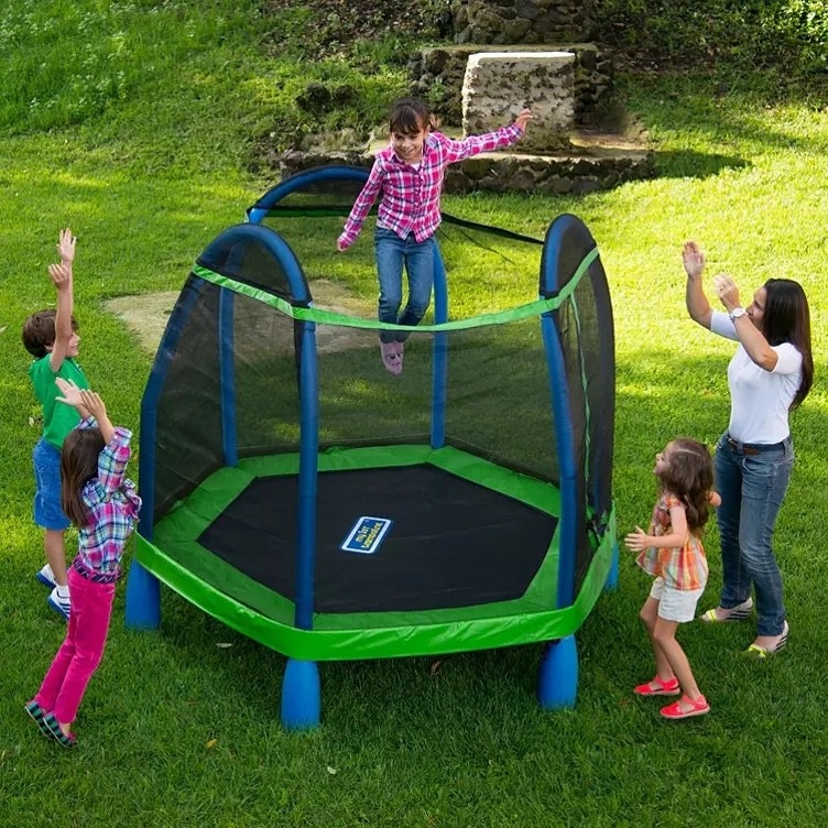 A family gathered around the trampoline as one child jumps on it