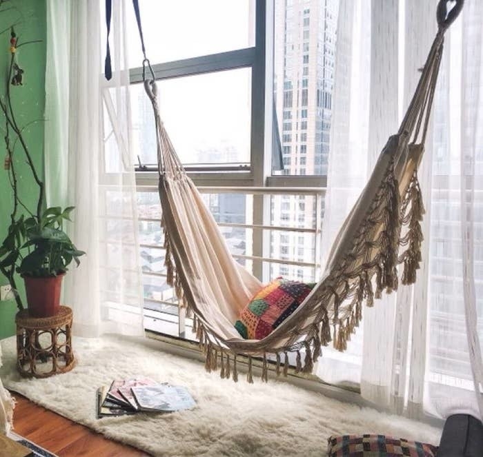 a hammock hanging indoors in front of a window