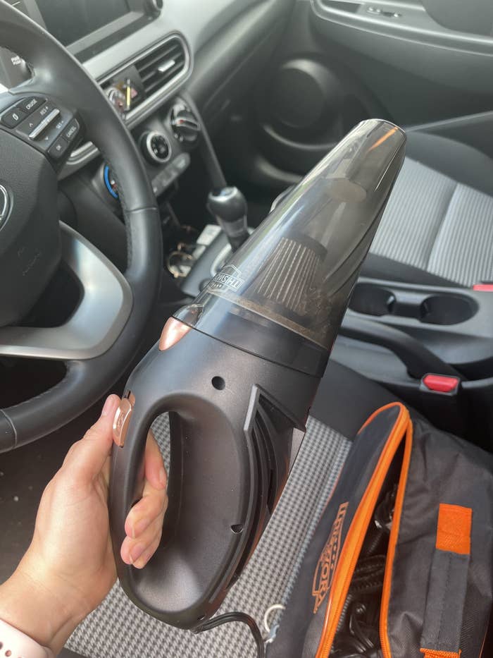 reviewer holding small black handled vacuum