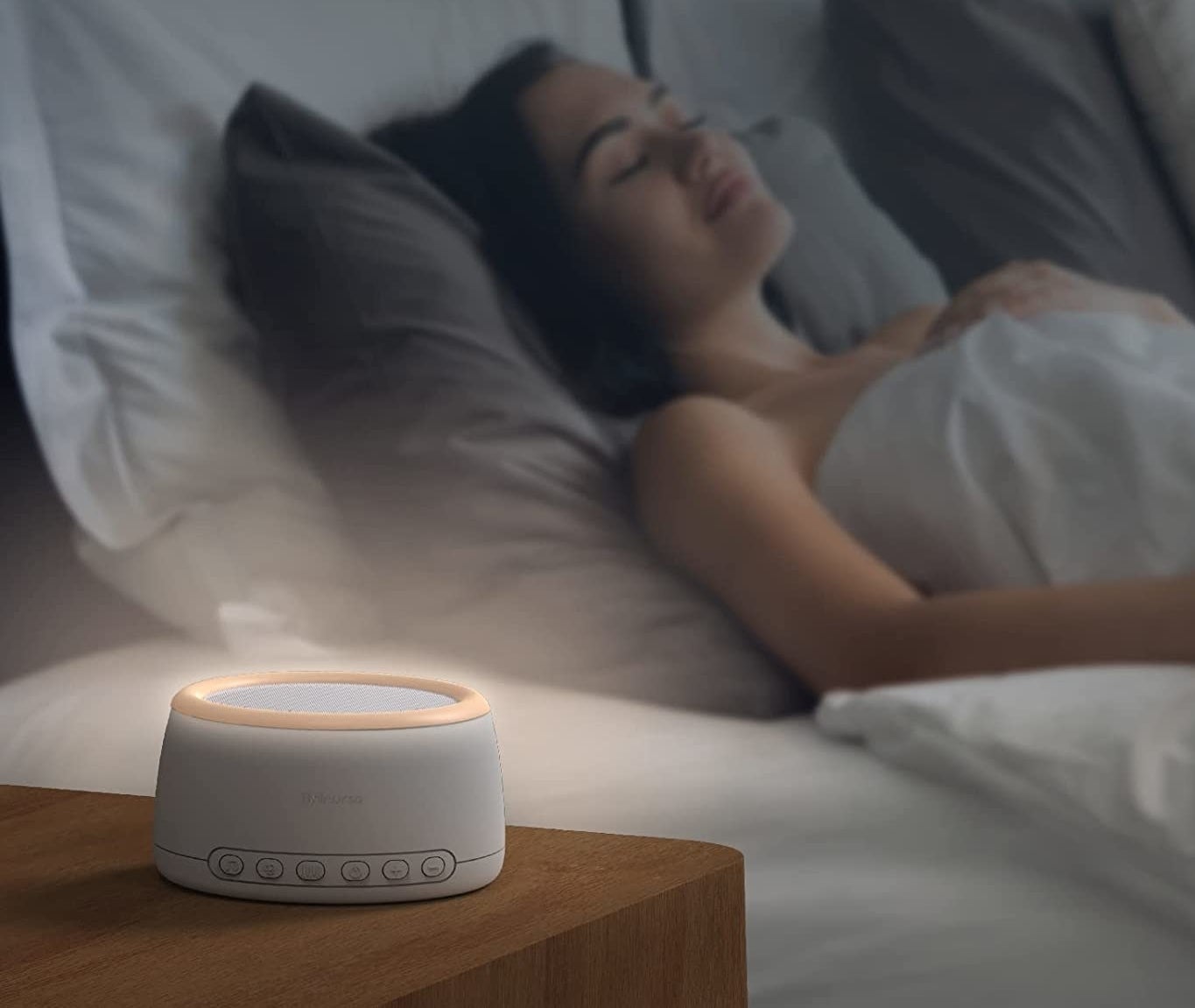 person sleeping in bed with the white noise machine on next to them