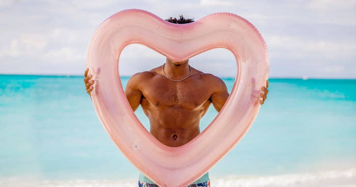 A shirtless man holds a heart balloon