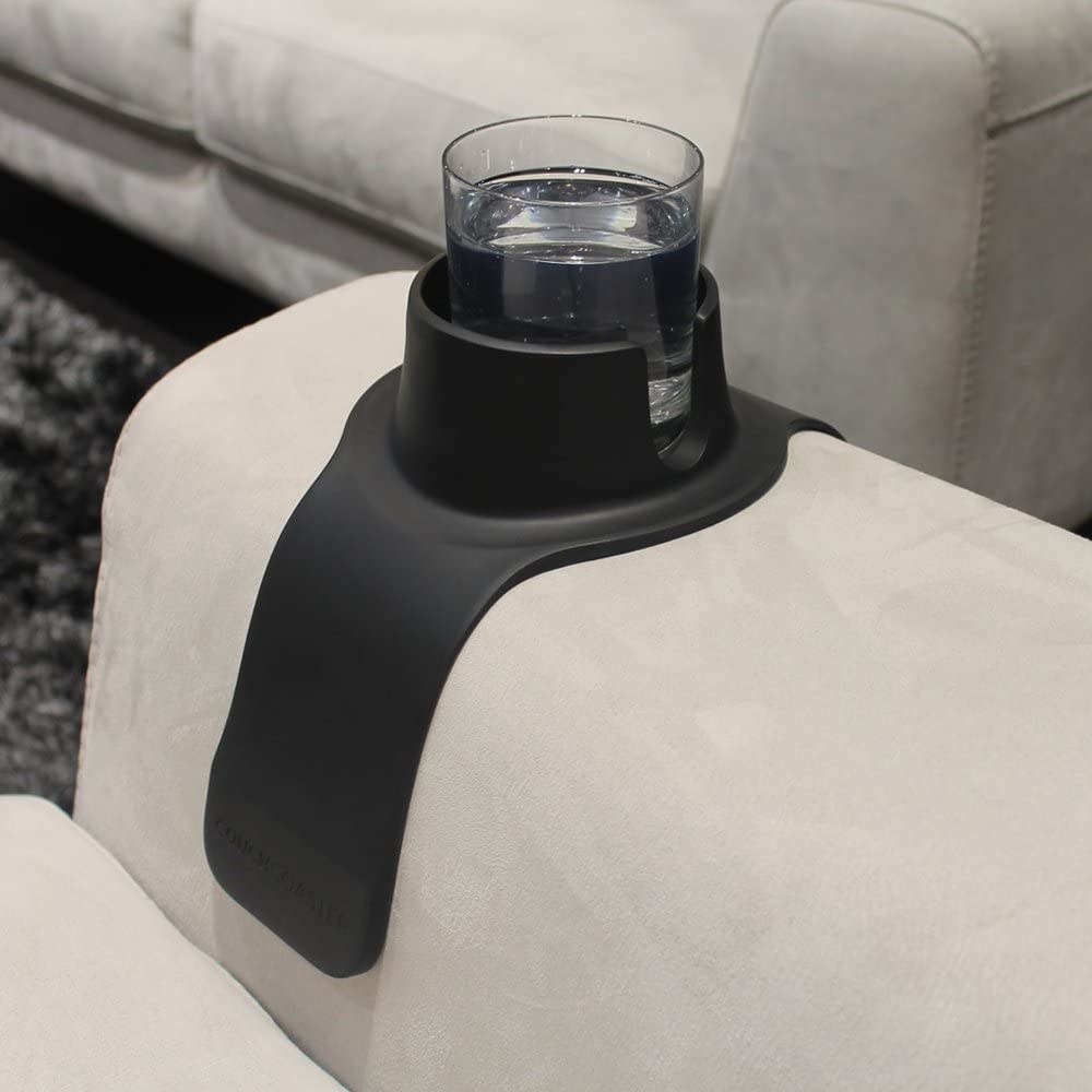 A couch armrest with a drink holder containing a glass of water