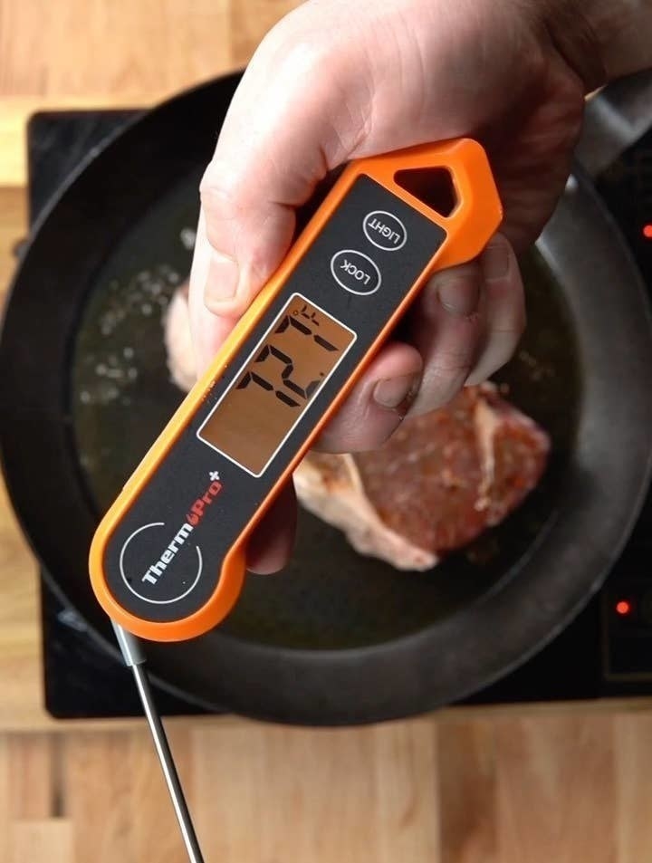 a person holding a thermometer over a skillet