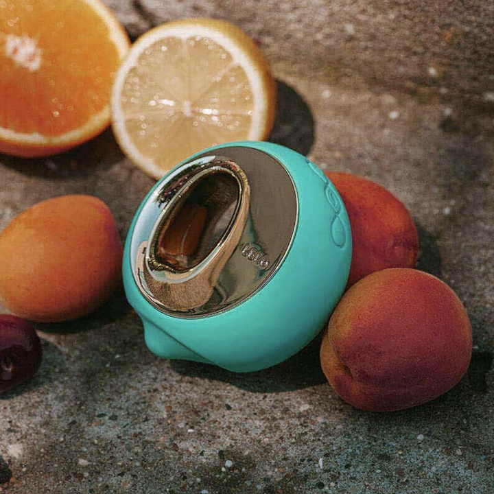 Teal clitoral stimulator surrounded by fruit