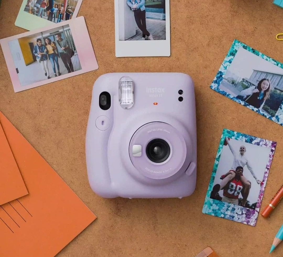 the camera on a desk beside instant photos