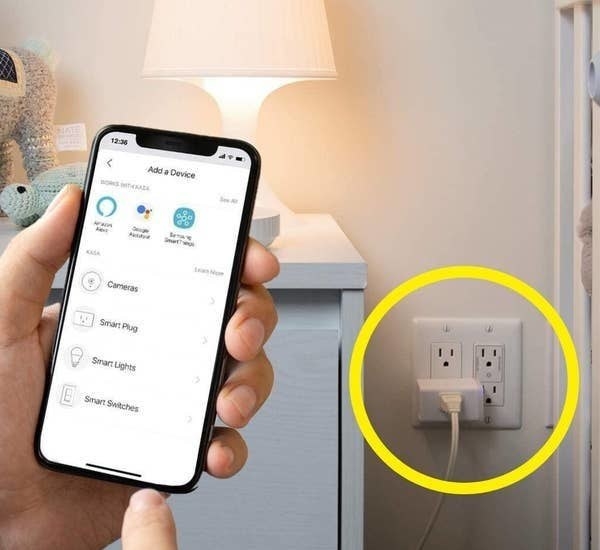 a person holding a phone that is connected to the smart plug
