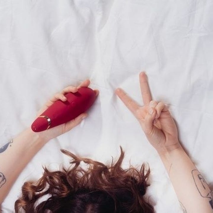 Model holding red suction vibrator in bed