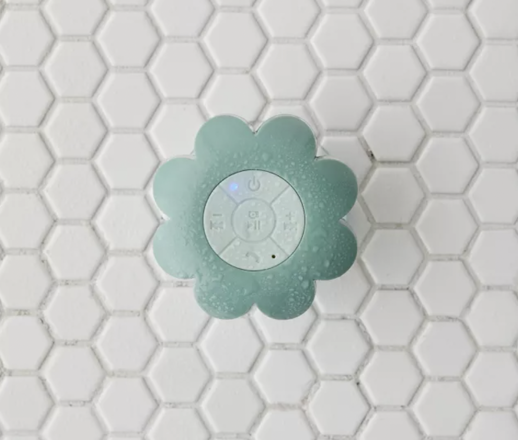 a flower shaped bluetooth speaker mounted to a tiled shower wall