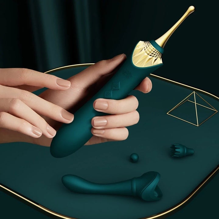 Model holding green and gold clitoral vibrator next to attachments