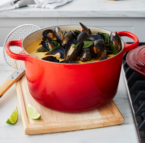 a red dutch oven filled with a seafood stew