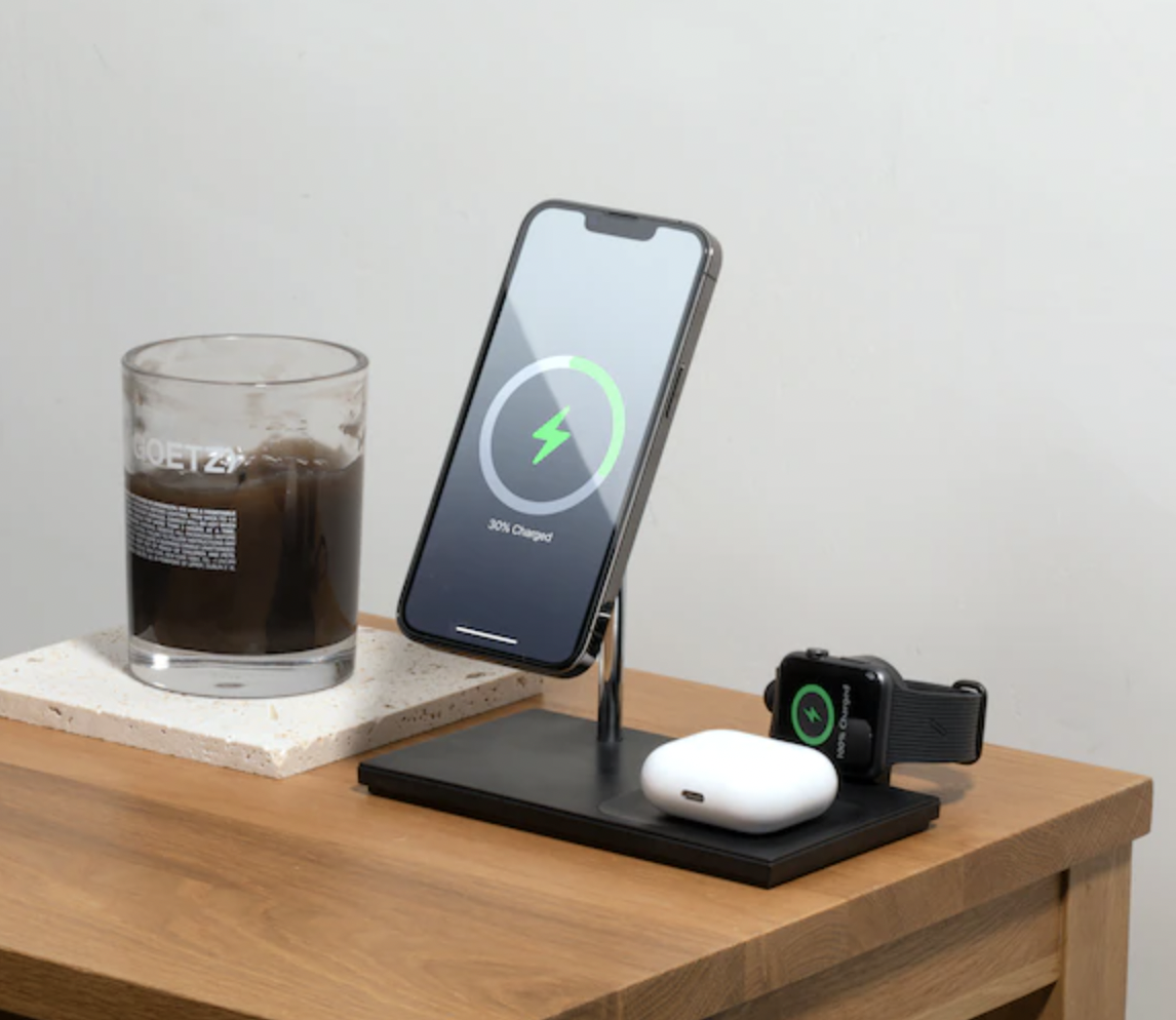 a charging station with an iphone, airpods, and an apple watch all powering up on it