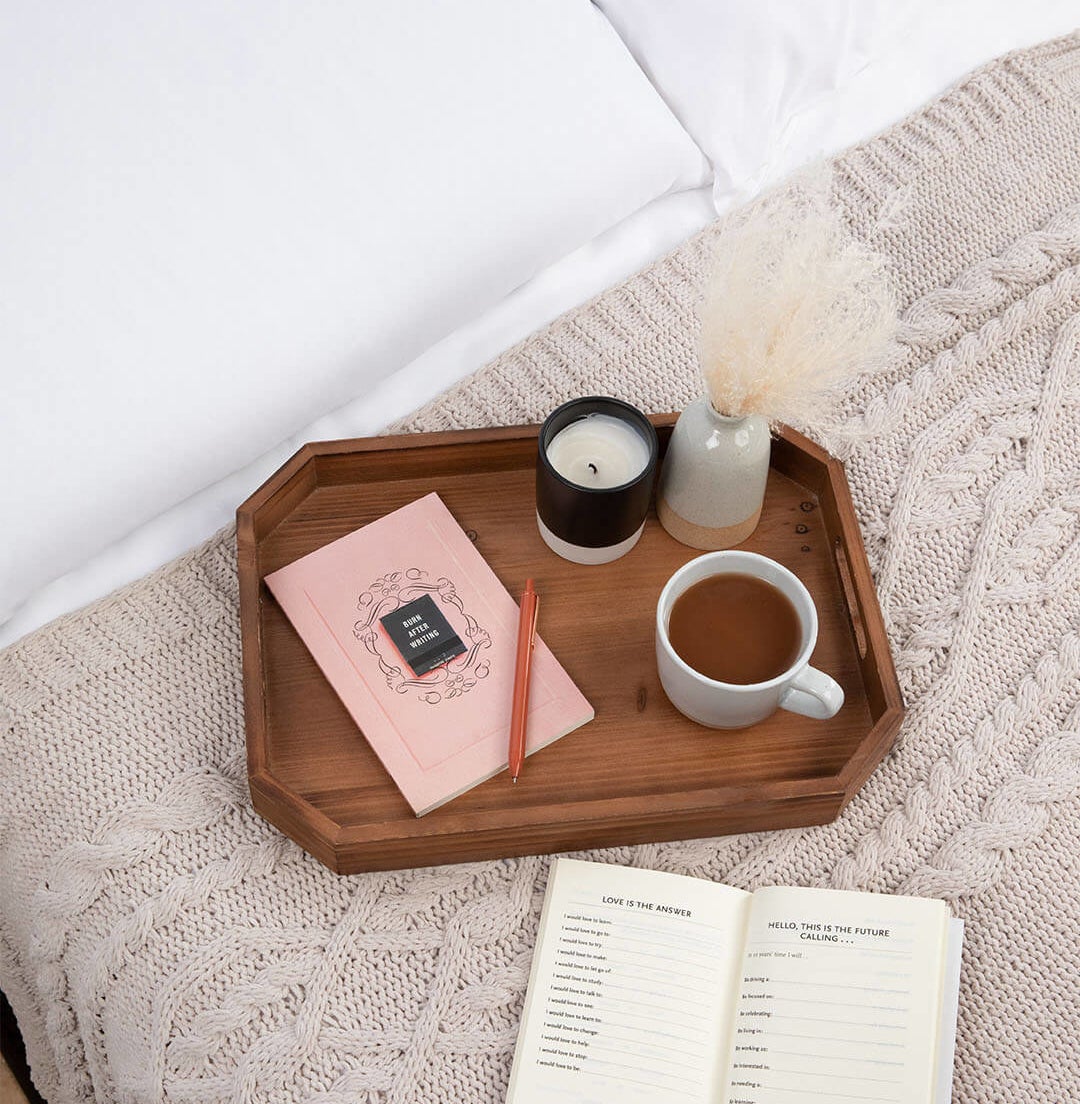 the book on a tray on top of a bed and another copy open on the bed