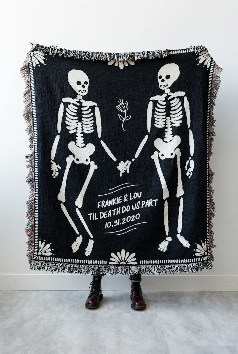 two skeletons with marriage date and words til death do us part on a woven blanket