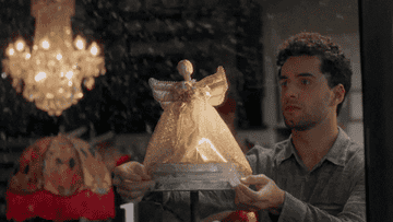 customer smiling outside a store window where she sees a christmas angel being placed on display. gif from the movie angel falls: a novel holiday