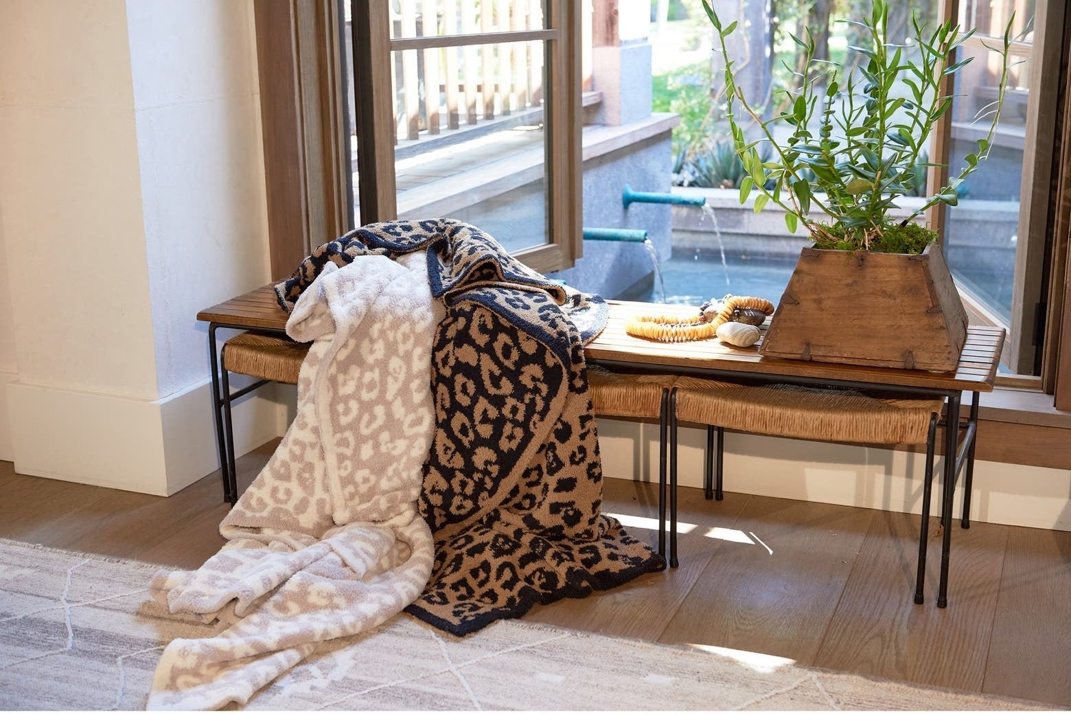 a cream and white leopard-print and a tan and black leopard-print blanket on a bench