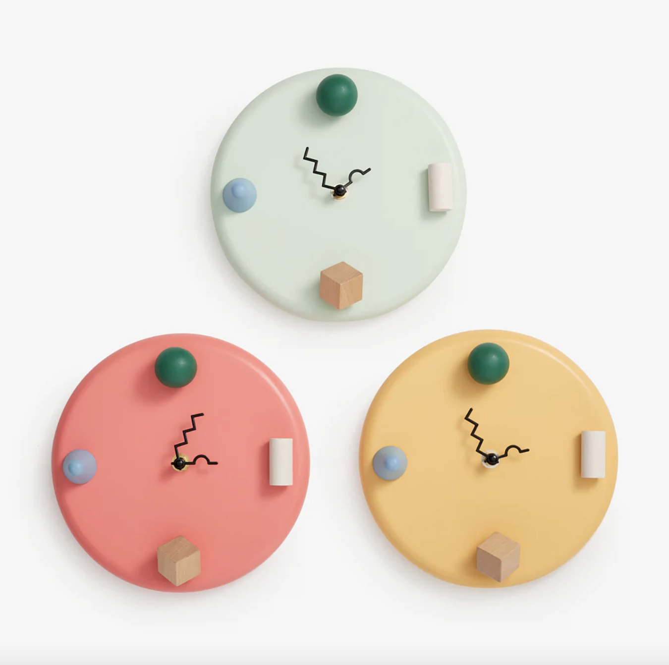 three wall clocks in mint, pink, and yellow