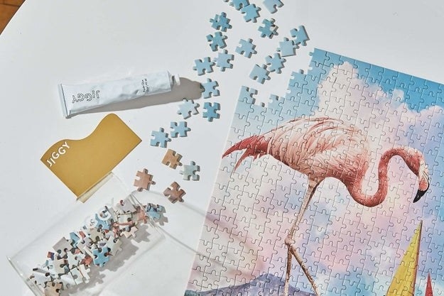 almost complete puzzle with flamingo design beside packaging and glue