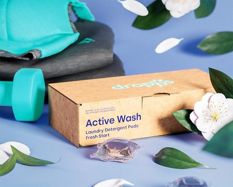 box of eco-friendly laundry detergent pods next to blue weight and workout clothes