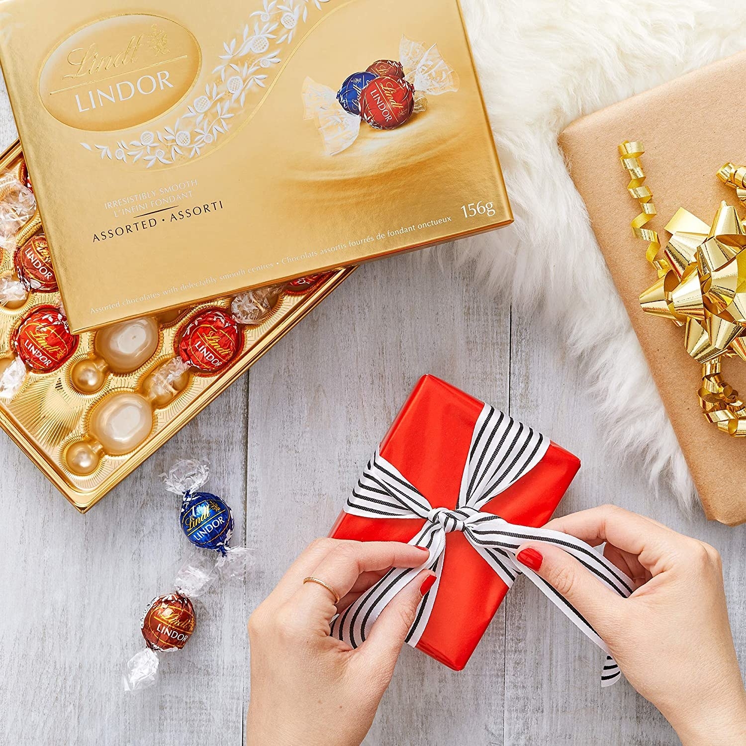 Hands tie a ribbon around a box of chocolates