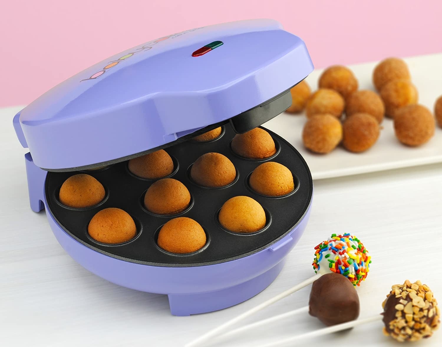 the cake pop maker beside cake pops and filled with cake pops