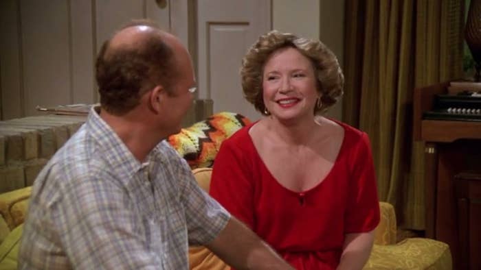 Red and Kitty sit on the couch, staring at each other and smiling.