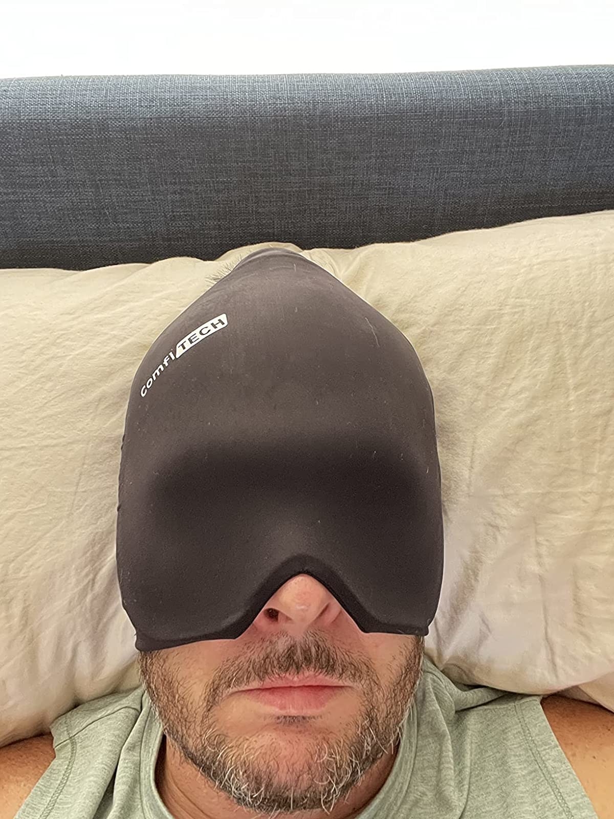 Reviewer laying down with the headache cap on covering down to their nose