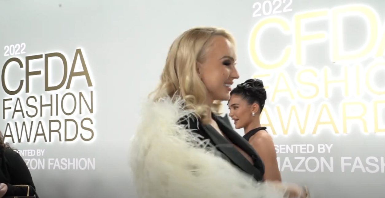 christine smiling while kylie walks the red carpet behind her