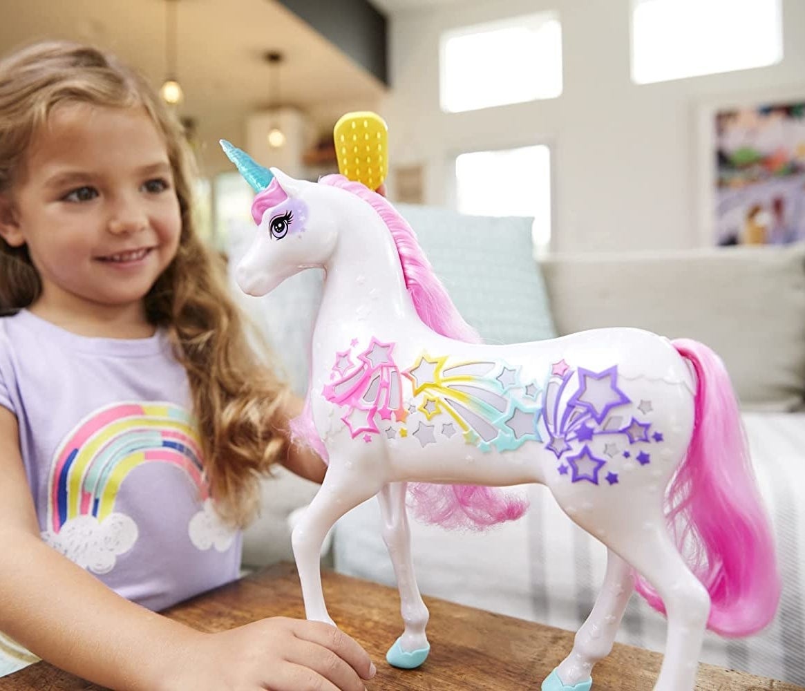 A kid playing with the Barbie unicorn