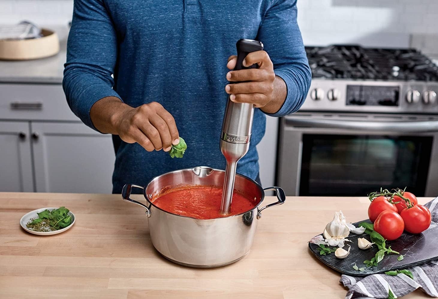 A person using the immersion blender to make pasta sauce