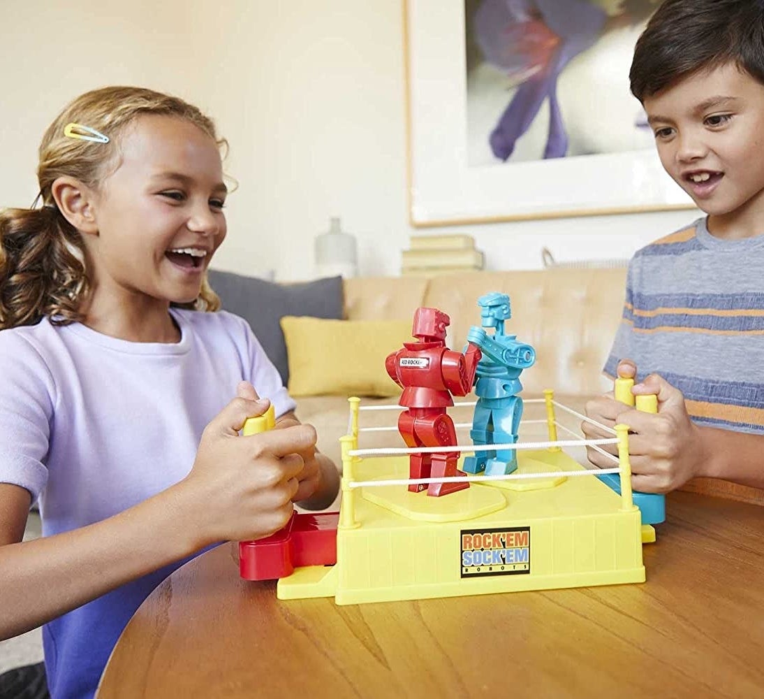 Two kids playing with the game on a wooden coffee table