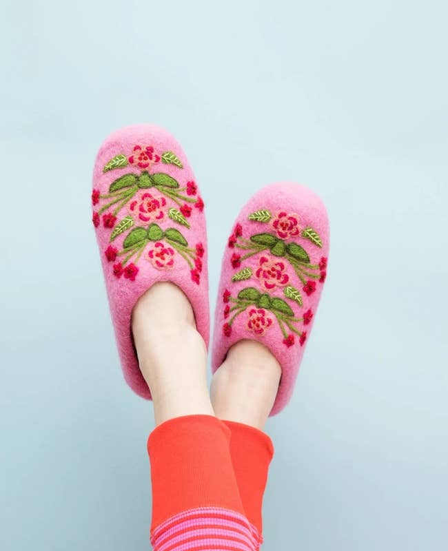a model wearing pink floral embroidered slippers