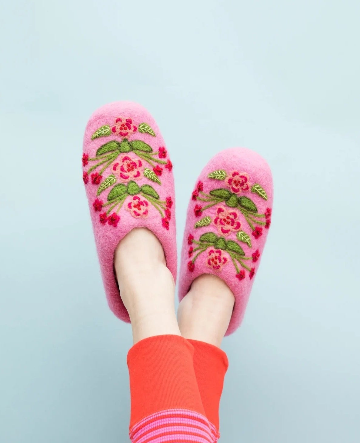 a model wearing pink floral embroidered slippers
