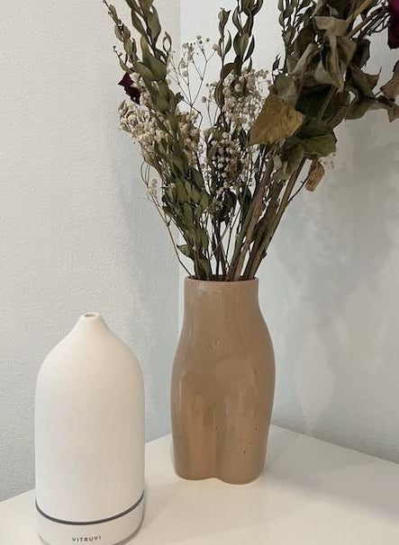 reviewer photo of a cream-colored diffuser next to a flower arrangement in a vase