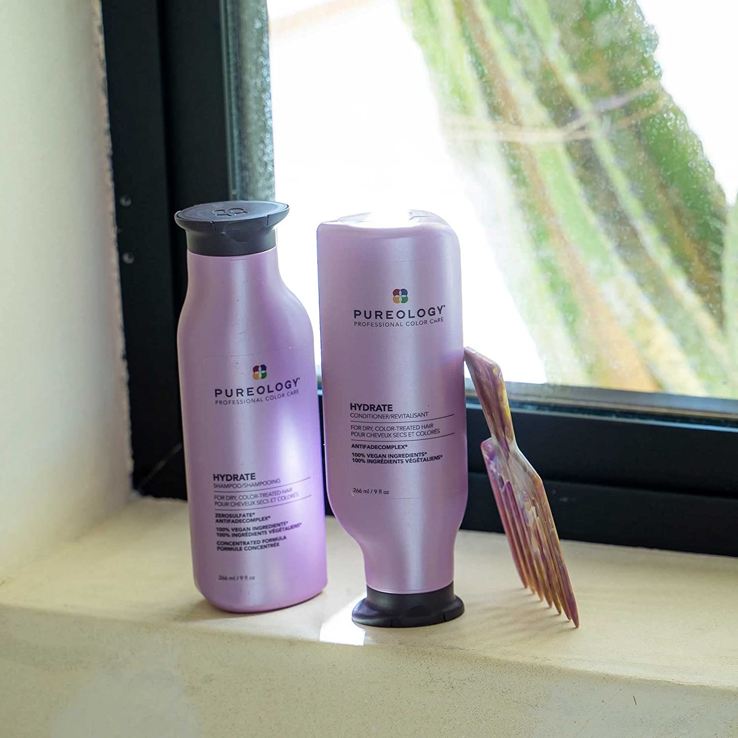 a bottle of shampoo and conditioner on a window ledge next to a comb