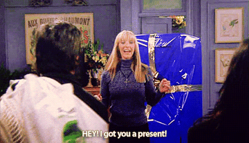 Phoebe from friends pointing at a gift and saying &quot;hey I got you a present&quot;