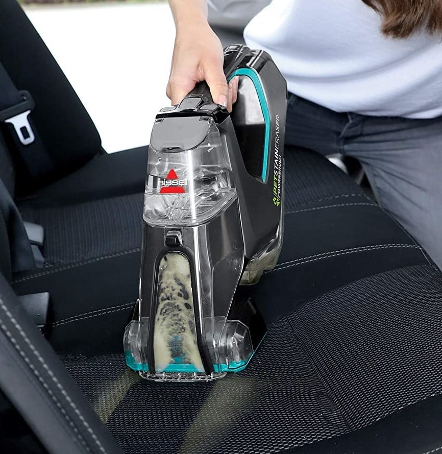 A person using the carpet cleaner in their car