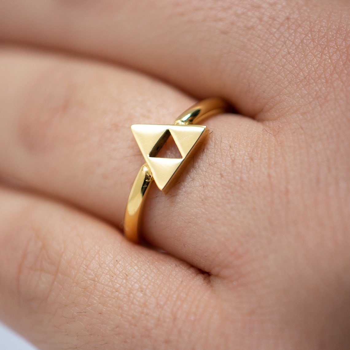 a silver and a gold triforce ring on a finger
