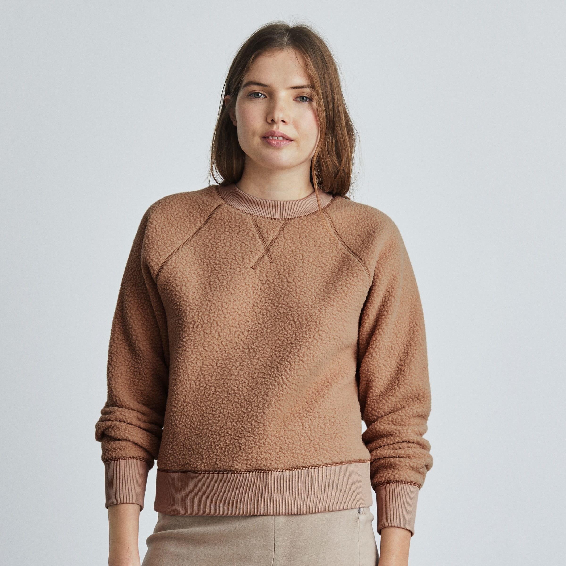 a model wearing the fleece pullover sweatshirt in light brown