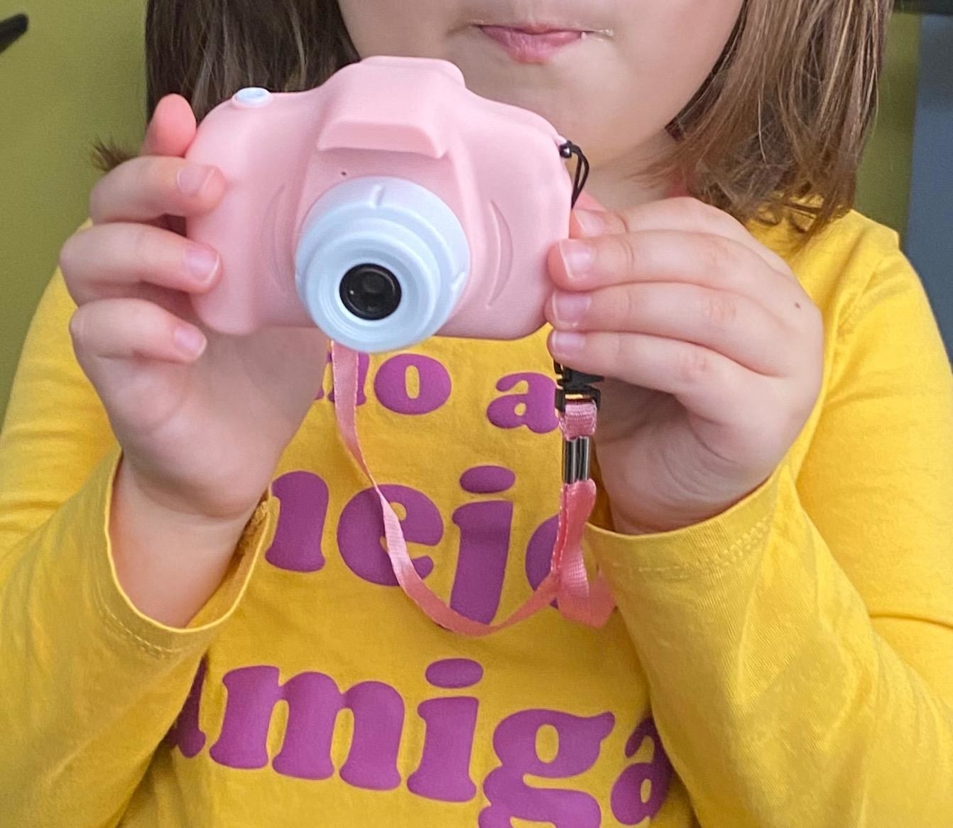 Reviewer&#x27;s photo of child holding the toy camera in pink