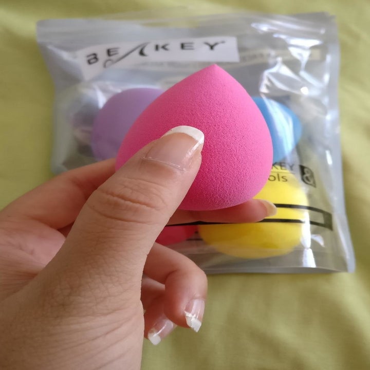a hand holding up a pink beauty sponge