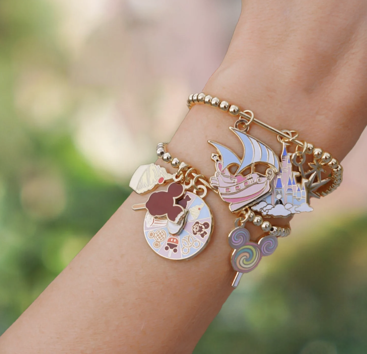 model wearing charm bar bracelet with various disney park inspired charms on it
