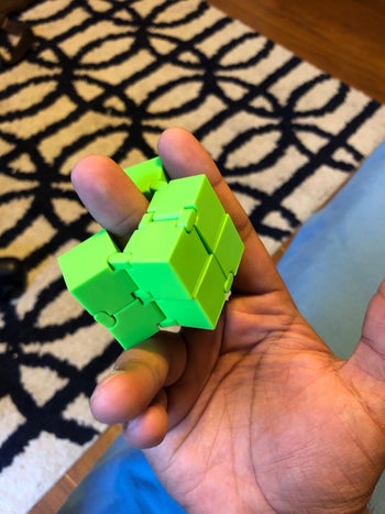 a hand playing with the infinity cube