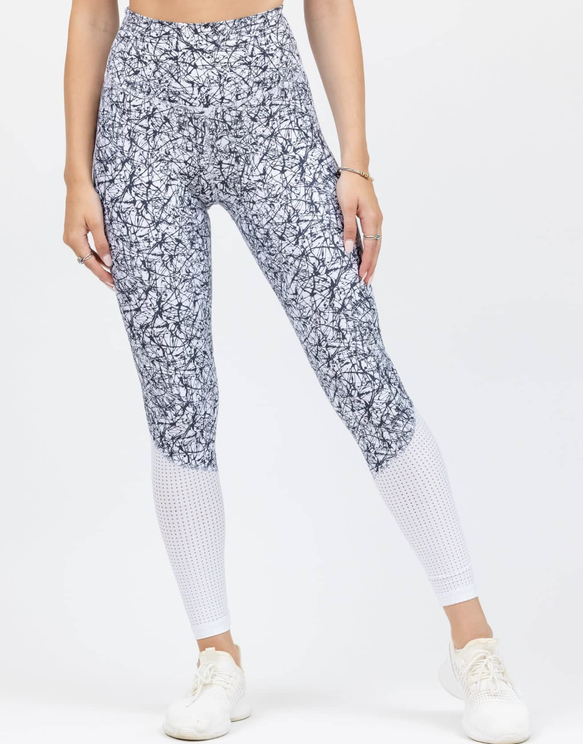 Model is wearing white leggings with a black abstract print and mesh on the calves