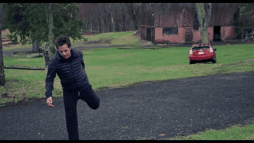Ben Stiller stretching as a car moves on its own behind him