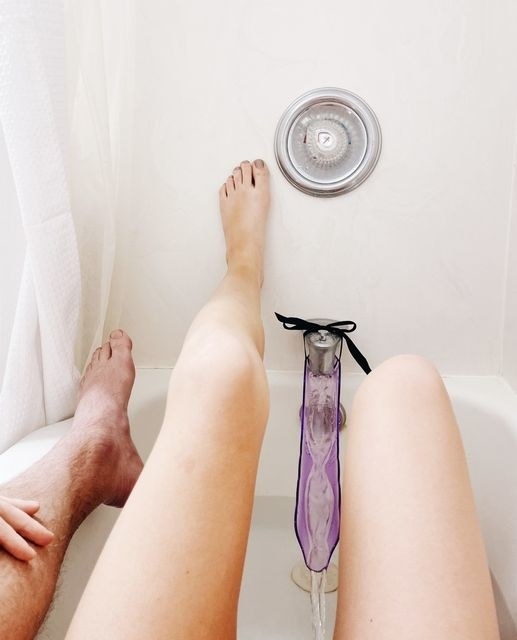 Couple in tub with purple faucet attachment