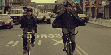Ben Stiller and Adam Driver riding bikes with no hands