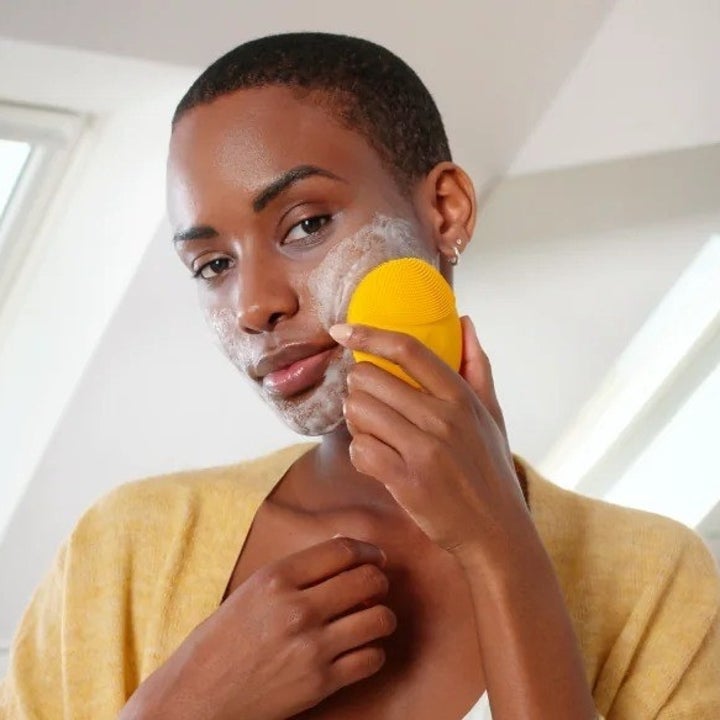 model using orange vibrating face cleanser brush