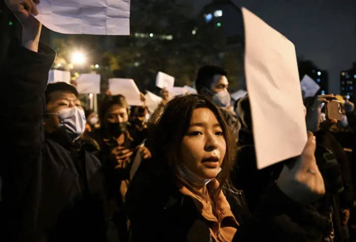 A group of protesters hold up blank white pieces of paper