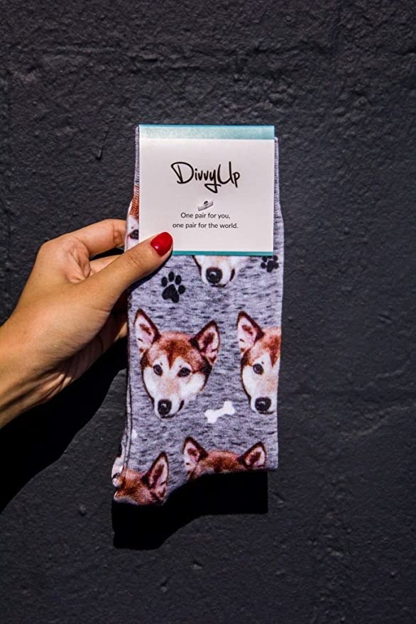 a hand holing up a pair of socks with a dog&#x27;s face on them